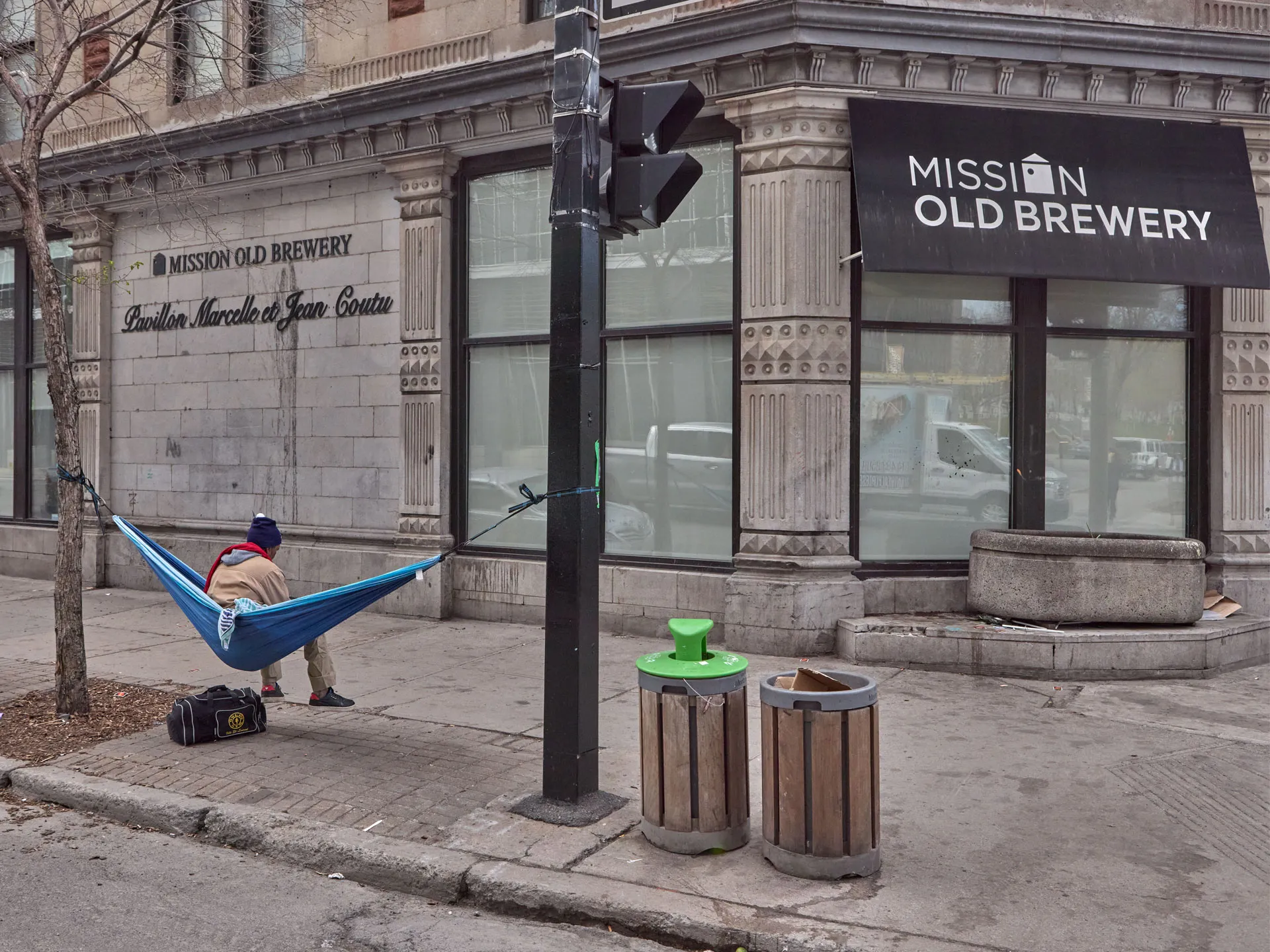Photo d'une personne en situation d'itinérance assise dans un hamac installé devant le Pavillon Webster de la Mission Old Brewery.