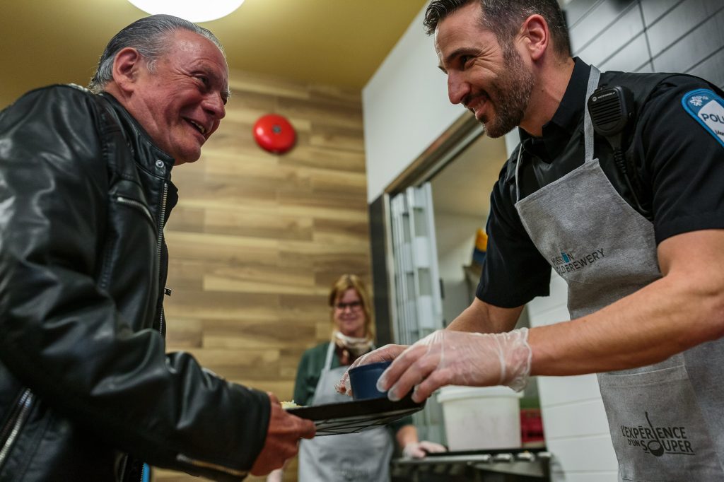 policier servant des repas à un homme sans-abri