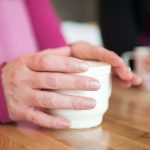 woman's hands around a cup of coffee