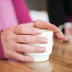 mains d'une femme autour d'une tasse de café