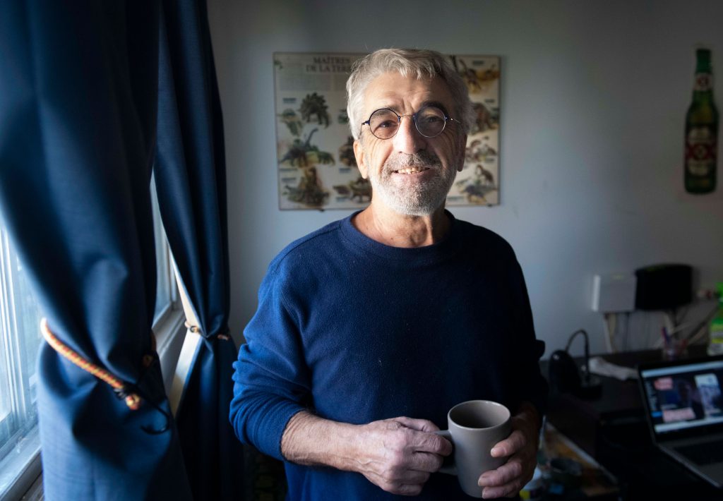 Un homme souriant tenant une tasse de café chez lui