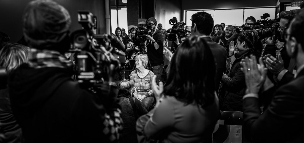 Woman getting a standing ovation in the middle of a crowd.