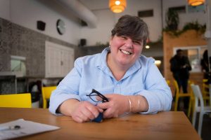 femme souriante avec chemise bleue dans une salle à manger